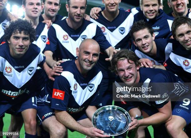 Kevin Muscat of the Victory holding a momento from the club poses for a team photo at the completion of the Kevin Muscat Testimonial match between...