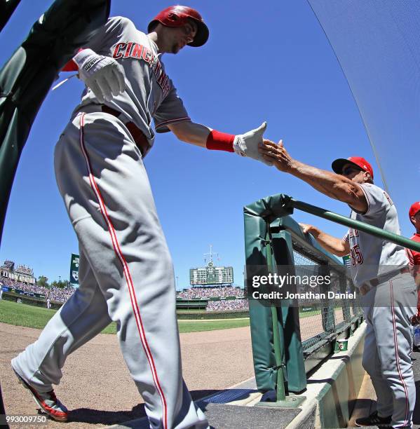 Scooter Gennett of the Cincinnati Reds is greeted by manager Jim Riggleman after scoring a run in the 4th inning against the Chicago Cubs at Wrigley...