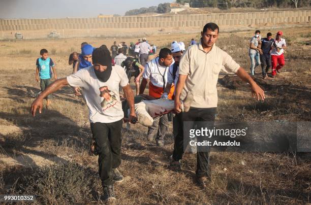 Palestinians carry an injured protestor, after Israeli security forces' intervention to a protest during a demonstration held within the "Great March...