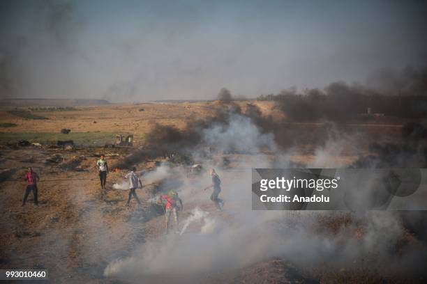 Palestinian protestors throw back Israeli security forces' tear gas canisters during a demonstration held within the "Great March of Return" near...