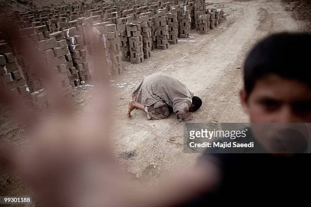 An Afghan child works prays at Sadat Ltd. Brick factory, on May 14, 2010 in Kabul, Afghanistan. Child labour is common at the brick factories where...