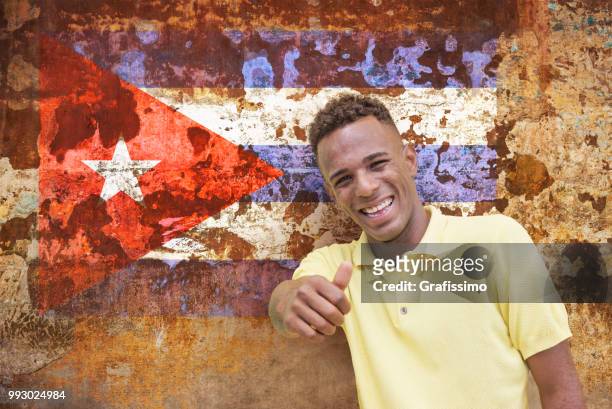 cuban man giving ok sign in cuba old havana with cuban flag - grafissimo stock pictures, royalty-free photos & images