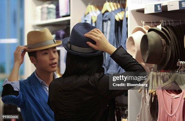 Customers examine hats at the Uniqlo store owned by Fast Retailing Co., in Shanghai, China, on Friday, May 14, 2010. Fast Retailing Co. Plans to...