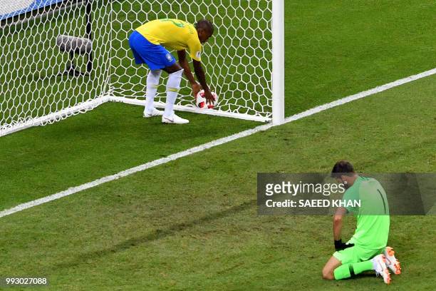 Brazil's midfielder Fernandinho picks up the ball as Brazil's goalkeeper Alisson reacts after conceding the second goal during the Russia 2018 World...