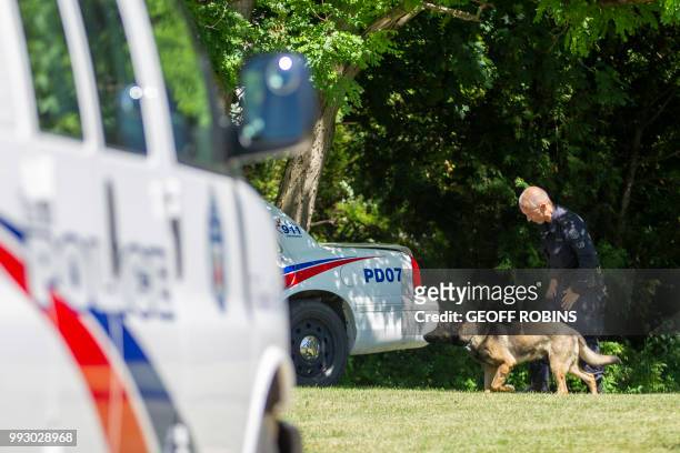 Toronto Police K9 officer and his dog walk near a ravine behind a home on Mallory Crescent in Toronto, Ontario, July 6, 2018 where human remains were...