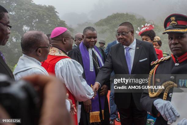 Malawi President Arthur Peter Mutharika followed by First Lady Getrude Mutharika, shakes hands with members of the officiating clergy on his arrival...