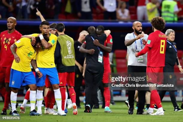 Thiago Silva and Marcelo both of Brazil look dejected as Marouane Fellaini of Belgium and Assistant Coach of Belgium Thierry Henry celebrate after...