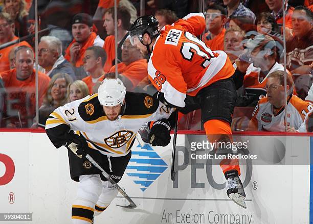 Andrew Ference of the Boston Bruins checks Darroll Powe of the Philadelphia Flyers in Game Six of the Eastern Conference Semifinals during the 2010...