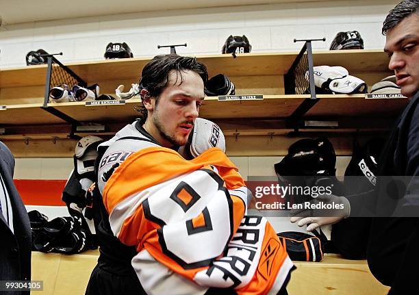 Danny Briere of the Philadelphia Flyers takes off his jersey to give to equipment manager Harry Bricker in the locker room after defeating the Boston...