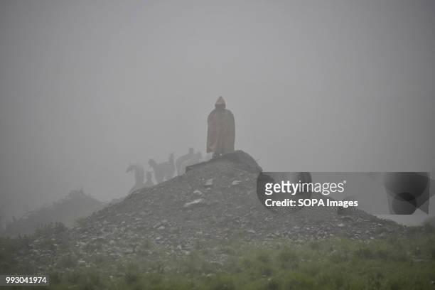 An Indian policeman stands guard as it rains during the traditional journey to the Amarnath cave. Thousands of pilgrims annually go to the remote...