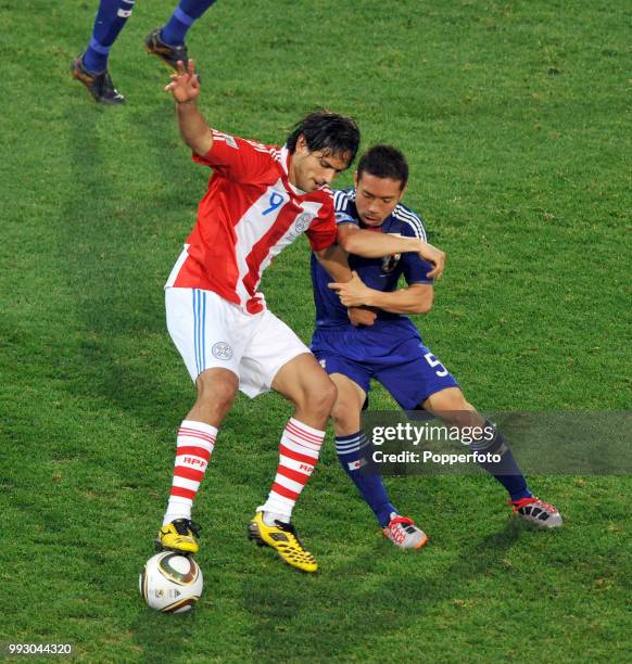 Roque Santa Cruz of Paraguay holds off the challenge of Yuto Nagatomo of Japan during a FIFA World Cup Round of 16 match at the Loftus Versfeld...