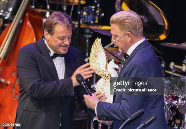 Organiser Joerg Mueller hands over a Pegasus trophy to former professional tennis player Boris Becker which he subsequently received as a 'Legend of...