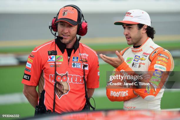Chase Elliott, driver of the Hooters Chevrolet, speaks with his crew chief Alan Gustafson on the grid during qualifying for the Monster Energy NASCAR...