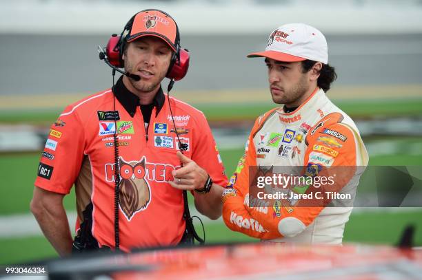 Chase Elliott, driver of the Hooters Chevrolet, speaks with his crew chief Alan Gustafson on the grid during qualifying for the Monster Energy NASCAR...