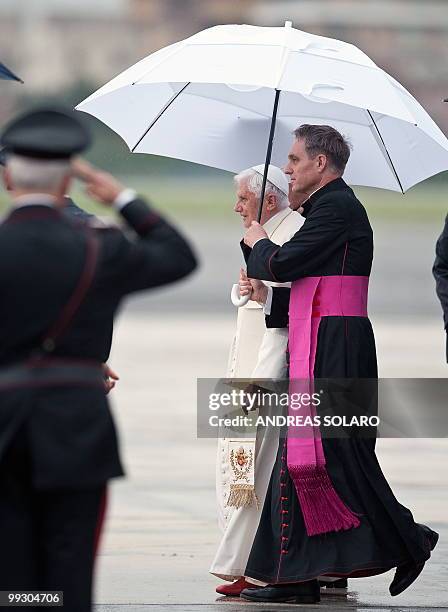 Pope Benedict XVI walks under an umbrello held by his personal secretary Georg Gaenswein as he disembarks from an Air Portugal plane, at the end of...