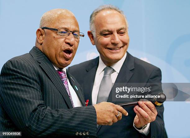 The COP23 president and prime minister of the Fiji Islands Frank Bainimarama receives the hammer from the prior COP22 president, Salaheddine Mezouar...