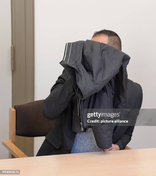 The accused of aggravated robbery covers his face with a jacket during the trial in the criminal justice building in Hamburg, Germany, 6 November...