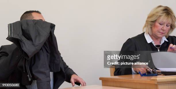 The accused of aggravated robbery covers his face with a jacket during the trial in the criminal justice building in Hamburg, Germany, 6 November...