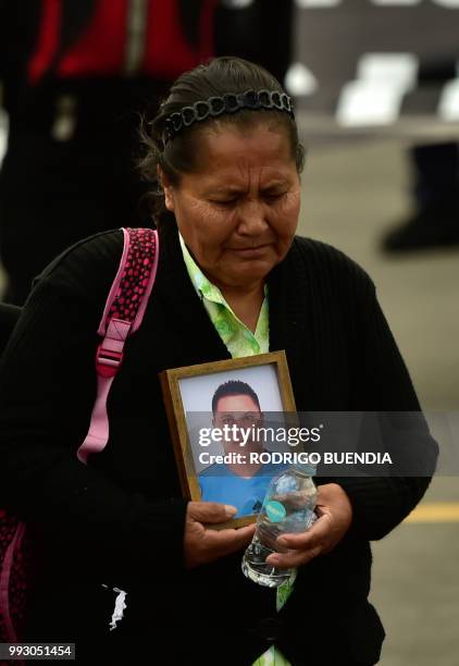 Relative of Ecuadorean slain Oscar Villacis holds his portrait as his remains arrive at Mariscal Sucre airport in Tababela, Ecuador on July 6, 2018....