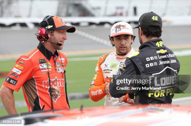Jimmie Johnson, driver of the Lowe's for Pros Chevrolet, and Chase Elliott, driver of the Hooters Chevrolet, talk with a crew member during...