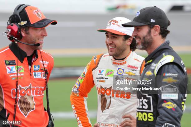 Jimmie Johnson, driver of the Lowe's for Pros Chevrolet, and Chase Elliott, driver of the Hooters Chevrolet, talk with a crew member during...
