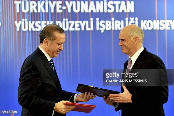 Greek Prime Minister George Papandreou, and his Turkish counterpart Recep Tayyip Erdogan exchange envelops after signing an agreement in Athens on...