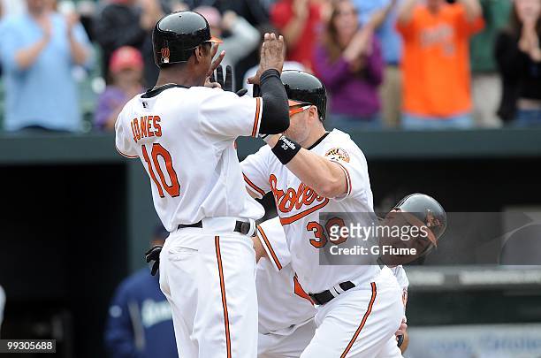 Luke Scott of the Baltimore Orioles is congratulated by Adam Jones and Ty Wigginton after hitting a grand slam home run in the eighth inning at...