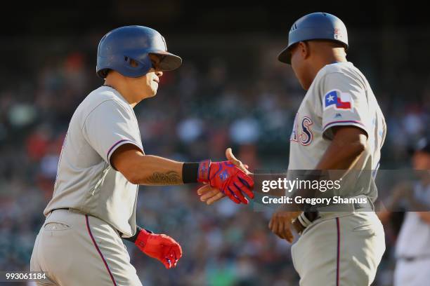 Shin-Soo Choo of the Texas Rangers celebrates his first inning home run with third base coach third base coach Tony Beasley while playing the Detroit...