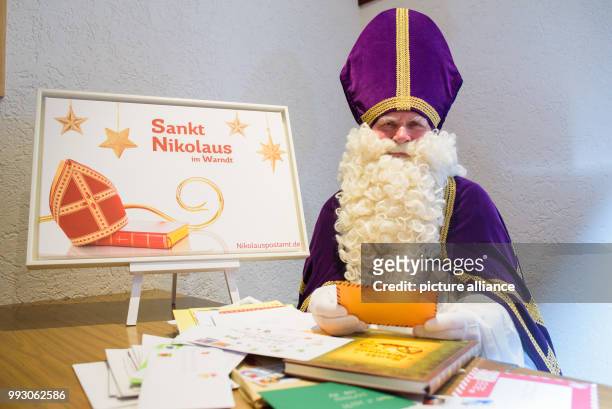 Performer in Nikolaus costume holding in his hands an air-mail letter that came along with other letters to the Nikolaus Post Office in St. Nikolaus,...