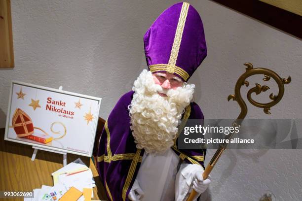 Performer in Nikolaus costume standing next to a graphic with the design of this year's special post stamp in St. Nikolaus, Germany, 06 November...