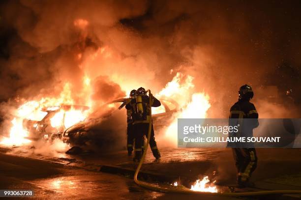 Firefighters work to put out a fire as cars burn in the Le Breil neighborhood of Nantes early on July 7, 2018. - A French policeman who shot dead a...