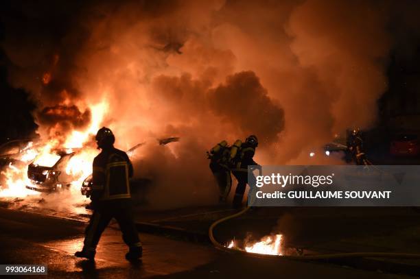 Firefighters work to put out a fire as cars burn in the Le Breil neighborhood of Nantes early on July 7, 2018. - A French policeman who shot dead a...