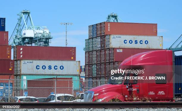 Container delivery truck passes containers stacked at the Port of Long Beach in Long Beach, California on July 6 including some from COSCO, the...