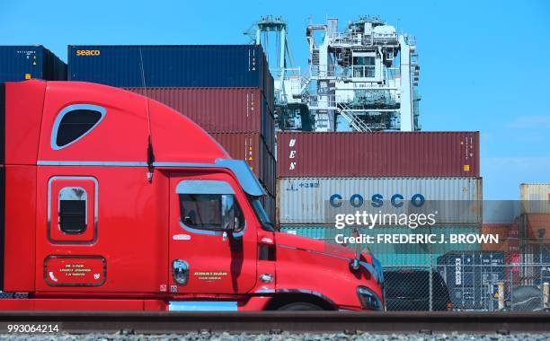 Container delivery truck passes containers stacked at the Port of Long Beach in Long Beach, California on July 6 including one from COSCO, the...