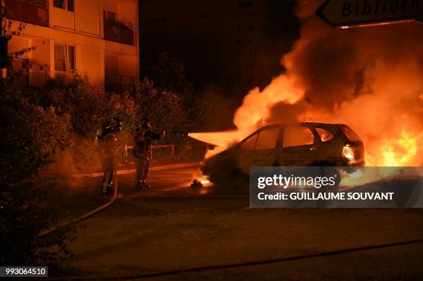 Firefighters work to put out a fire as cars burn in the Le Breil neighborhood of Nantes early on July 7, 2018. - A French policeman who shot dead a...