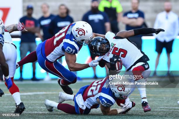 Fullback Patrick Lavoie and running back Ryder Stone of the Montreal Alouettes grab a hold of defensive back Loucheiz Purifoy of the Ottawa Redblacks...