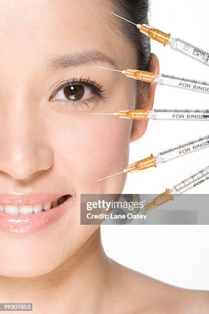 a row of syringes near a young woman's face - bad botox stock pictures, royalty-free photos & images