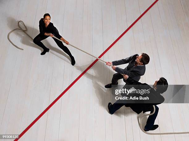 business men pulling woman with rope - stubborn stock-fotos und bilder