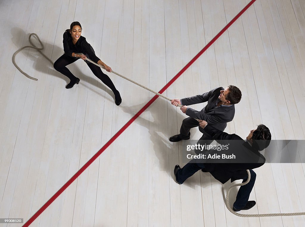 Business men pulling woman with rope