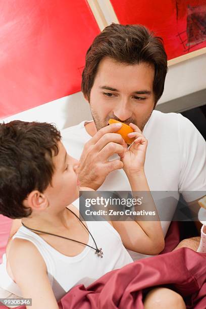 father and son having breakfast in bed - dietramszell stock pictures, royalty-free photos & images