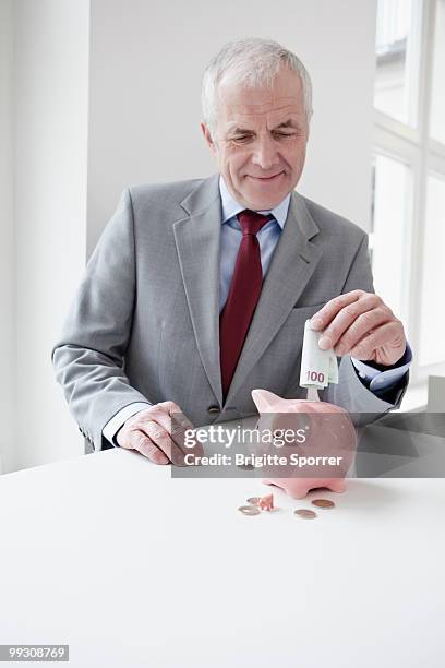 man putting banknote into piggy bank - brigitte sporrer stock pictures, royalty-free photos & images