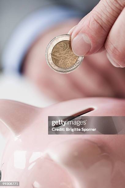 hand putting coin into piggy bank - boomer banks fotografías e imágenes de stock