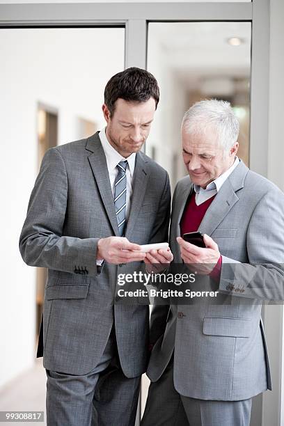 2 businessmen with handhelds - brigitte sporrer stock pictures, royalty-free photos & images