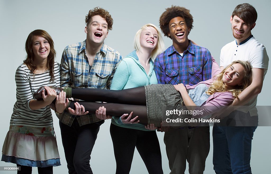 5 young adults carrying young woman