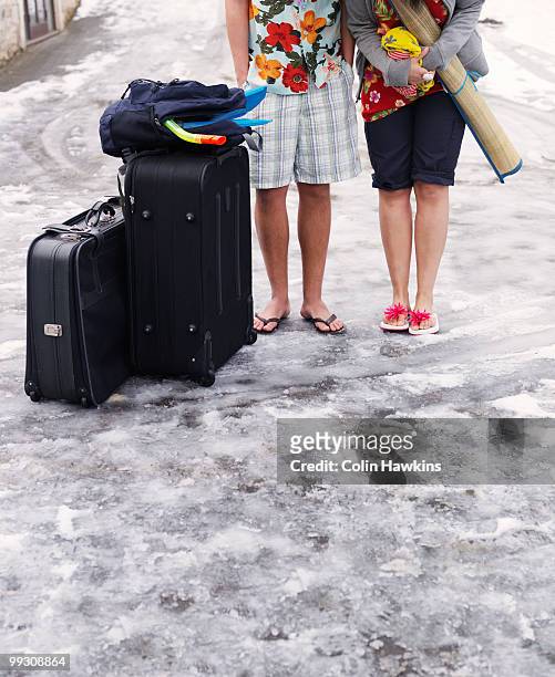 couple standing in snow with suitcases - colin hawkins stock pictures, royalty-free photos & images