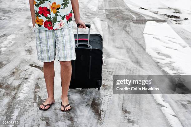 man in summerwear with suitcase in snow - colin hawkins stock pictures, royalty-free photos & images