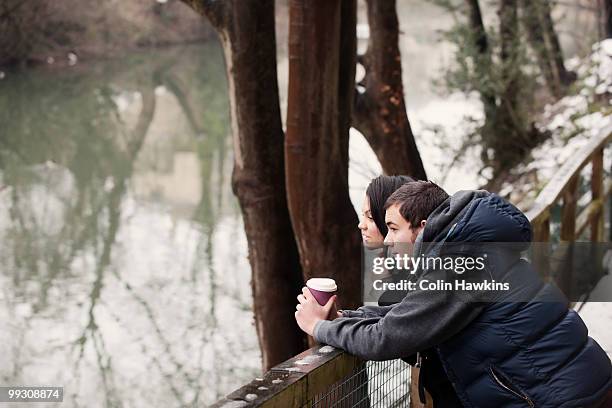 couple relaxing by river in winter - colin hawkins stock pictures, royalty-free photos & images