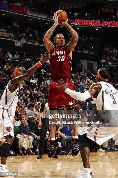 Michael Beasley of the Miami Heat shoots a jump shot against Stephen Jackson and Gerald Wallace of the Charlotte Bobcats during the game at Time...