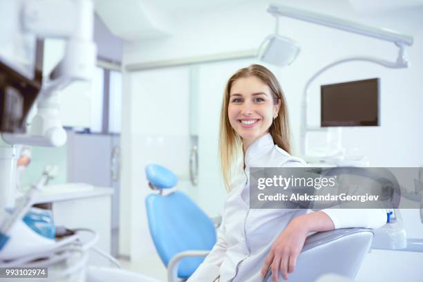 cute dentist technician smiling while sitting in dental clinic - dentists stock pictures, royalty-free photos & images