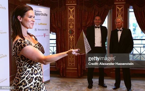 Katarina Witt poses with the Goldene Sportpyramide Award whilst Brandenburg's Minister President Matthias Platzeckat and Juergen Hubbert look on at...